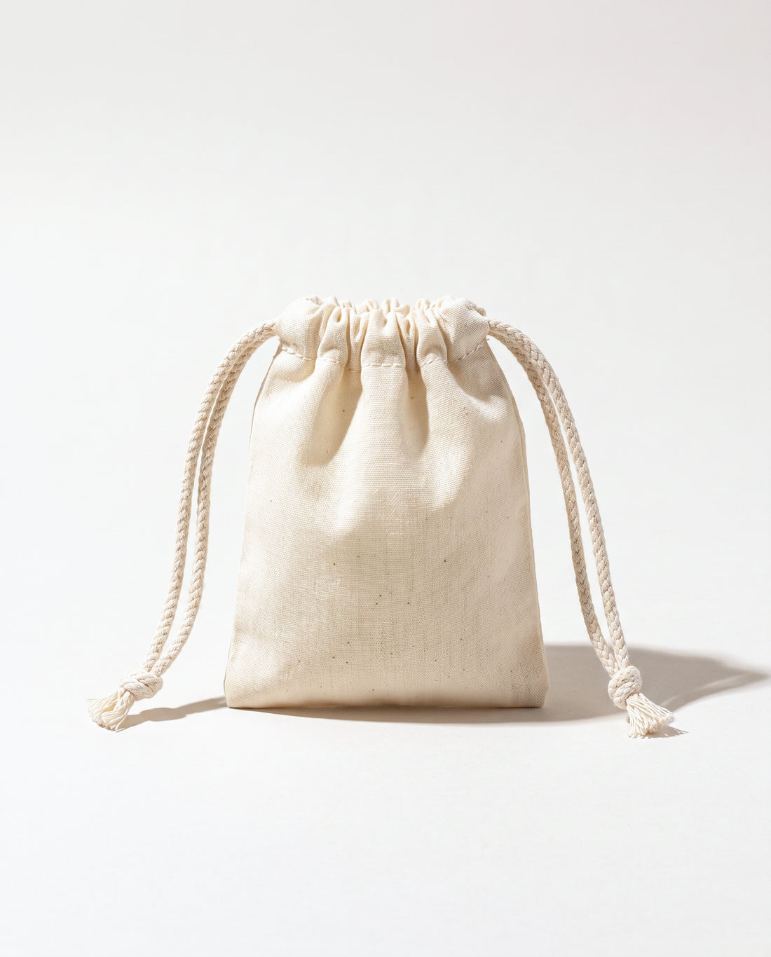 Plain natural cotton muslin double drawstring bag with braided cotton cords, white background