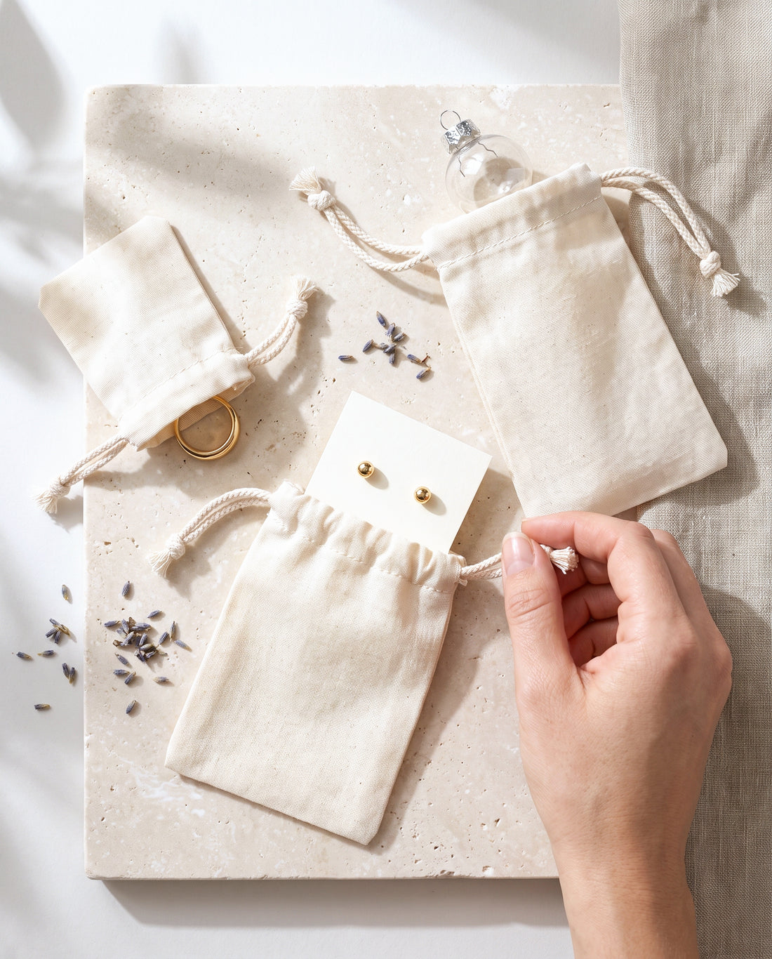 Natural cotton muslin drawstring bags in use for rings, earrings and tea samples