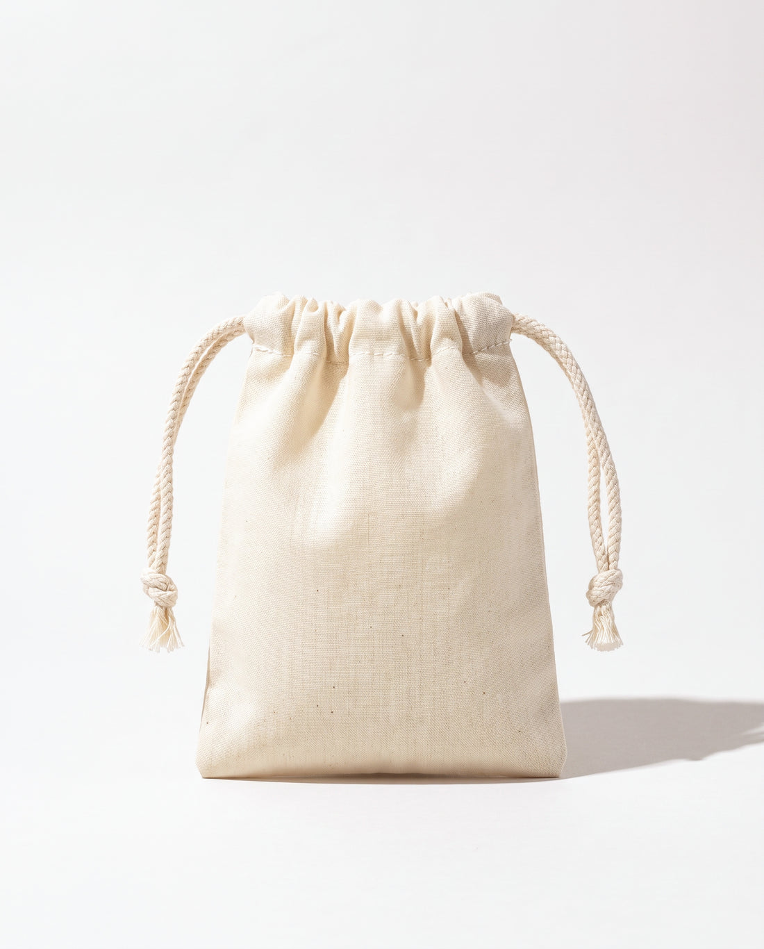 Plain natural cotton muslin double drawstring bag with braided cotton cords, white background