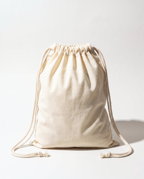 Plain natural cotton muslin double drawstring bag with braided cotton cords, white background