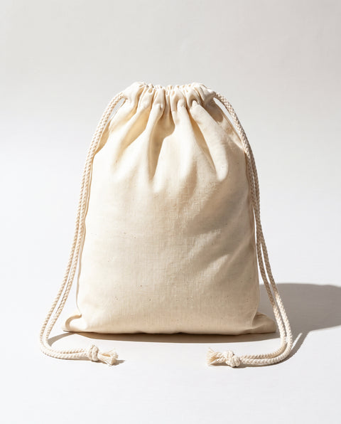 Plain natural cotton muslin double drawstring bag with braided cotton cords, white background